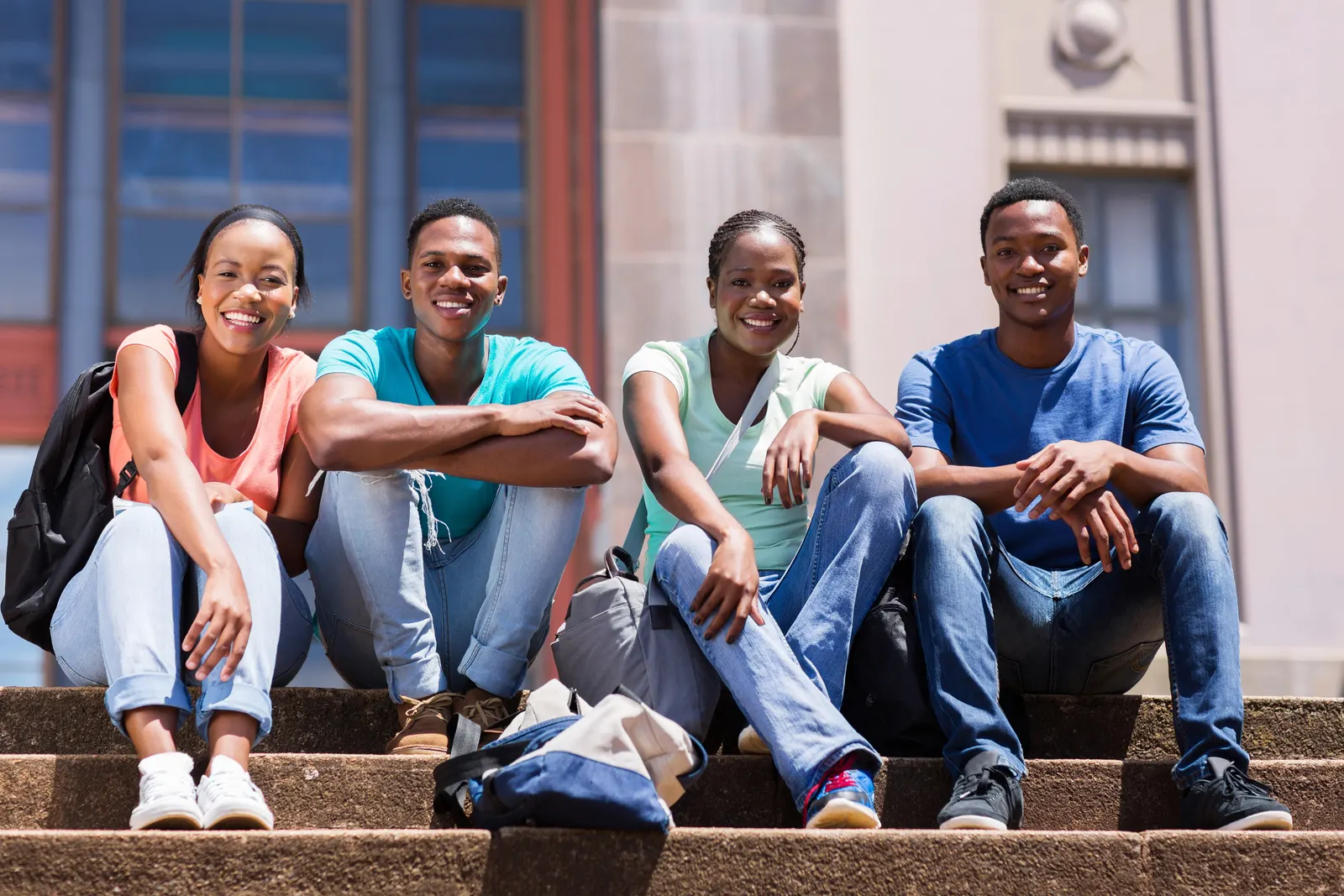 Four university students sitting together on the steps of a campus building
